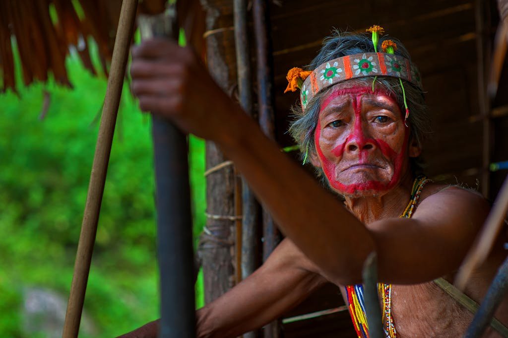 Portrait of an indigenous man with traditional face paint, wearing a vibrant headband.